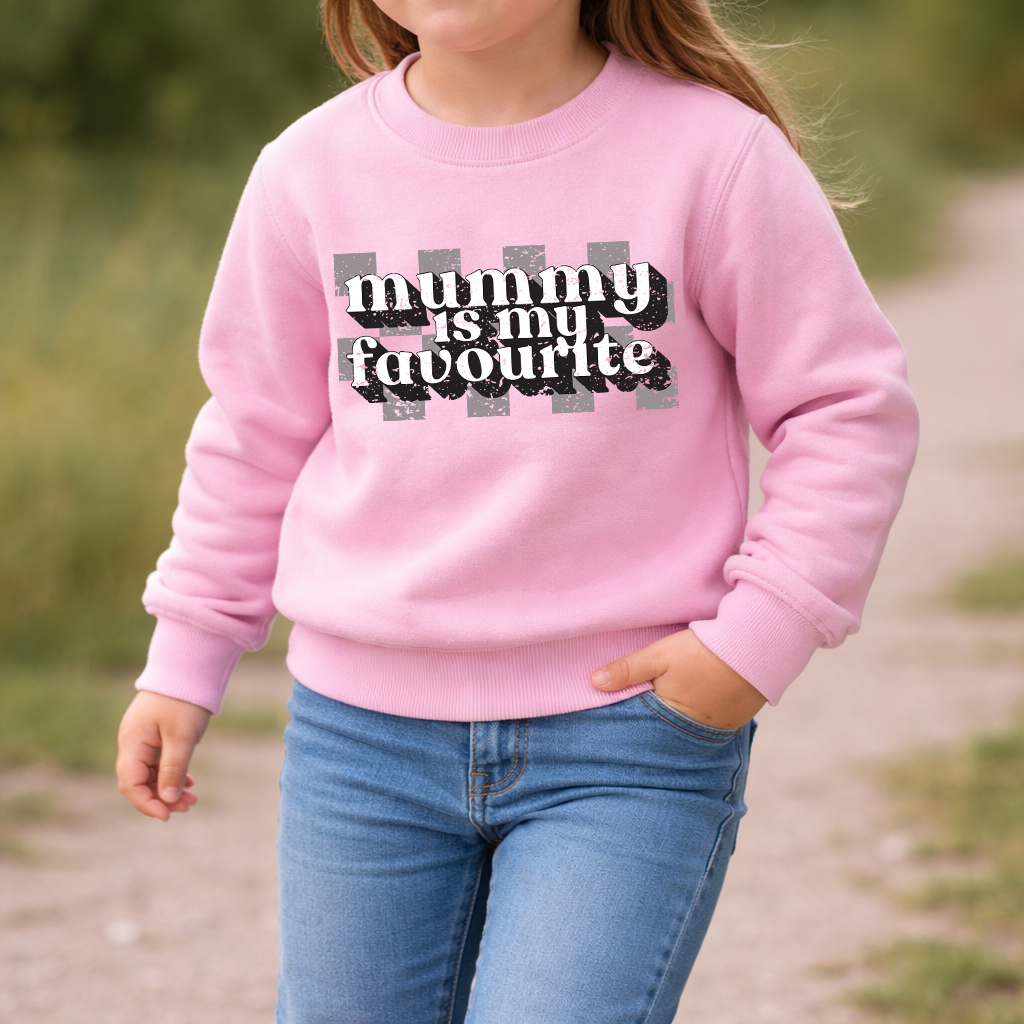 Child wearing a pink sweatshirt with 'mummy is my favourite' text outdoors.