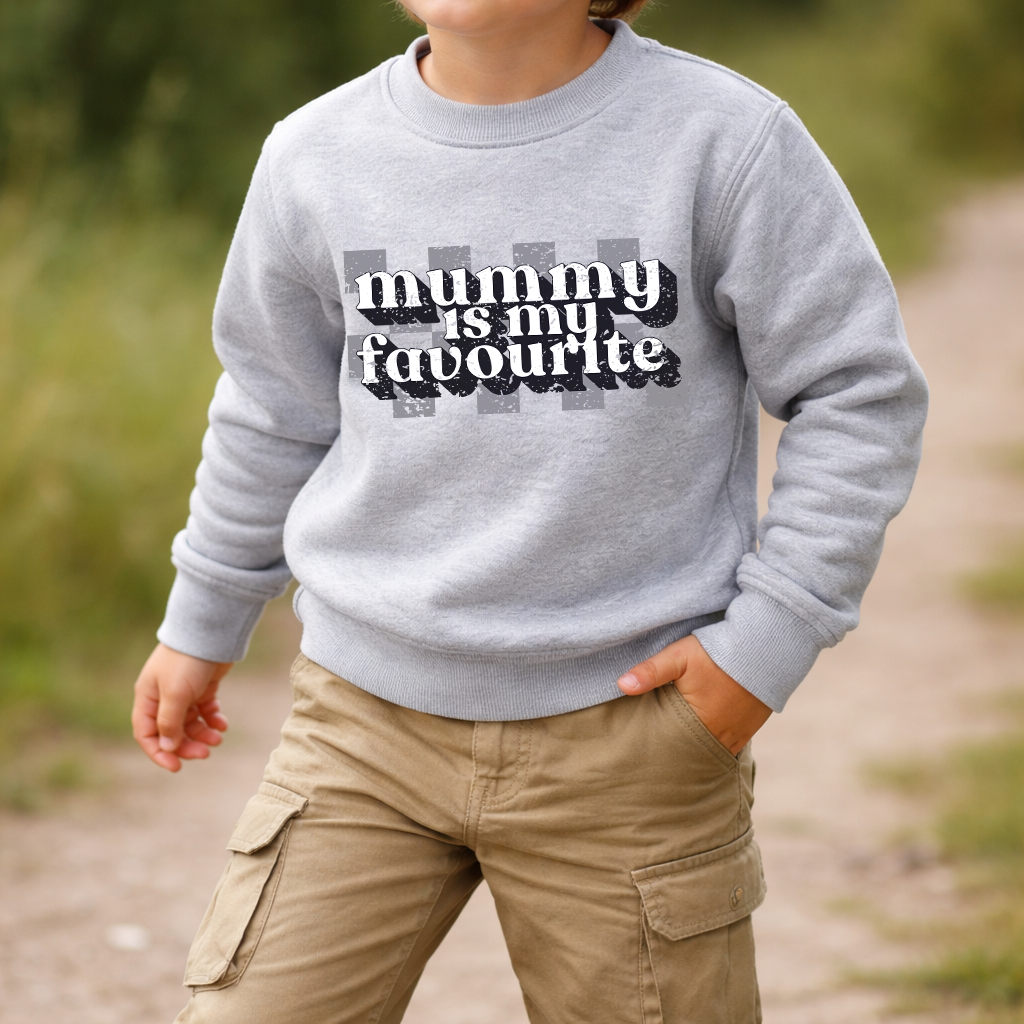 Child wearing a gray sweatshirt with 'mummy is my favourite' text outdoors.
