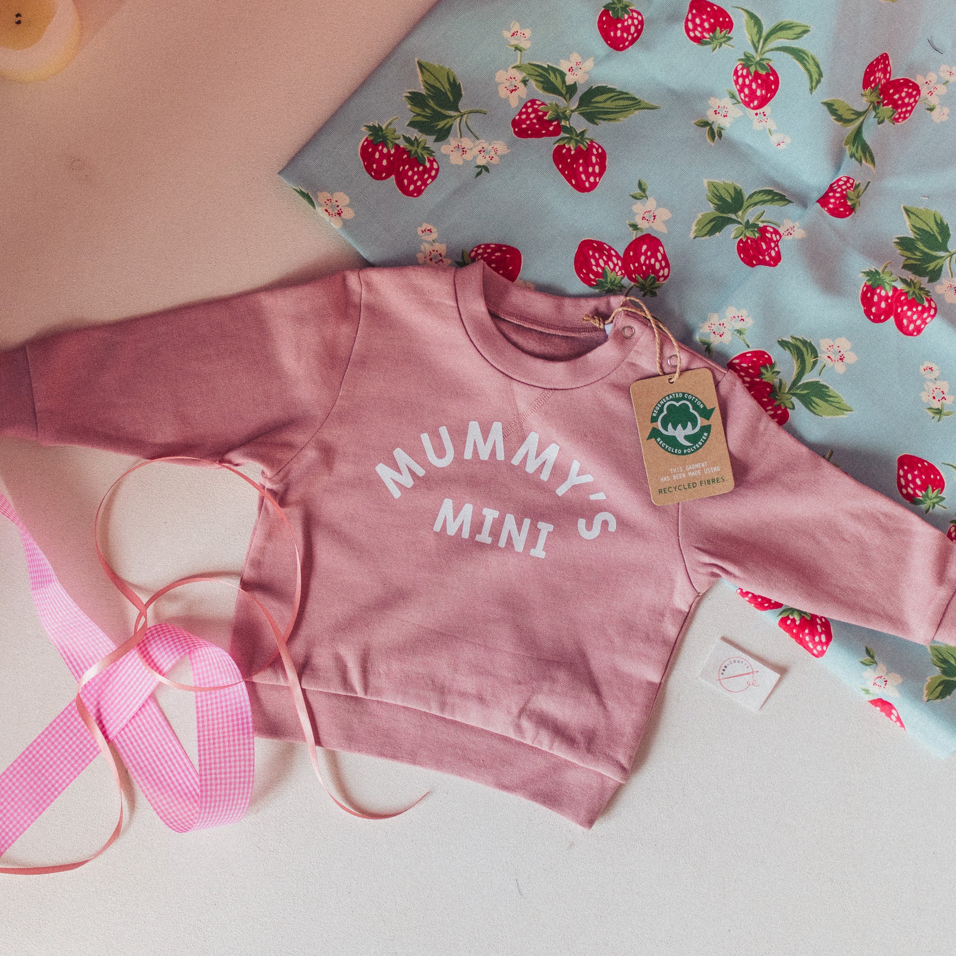 View of a charming pink children's sweatshirt with a sweet 'Mummy's Mini' design.