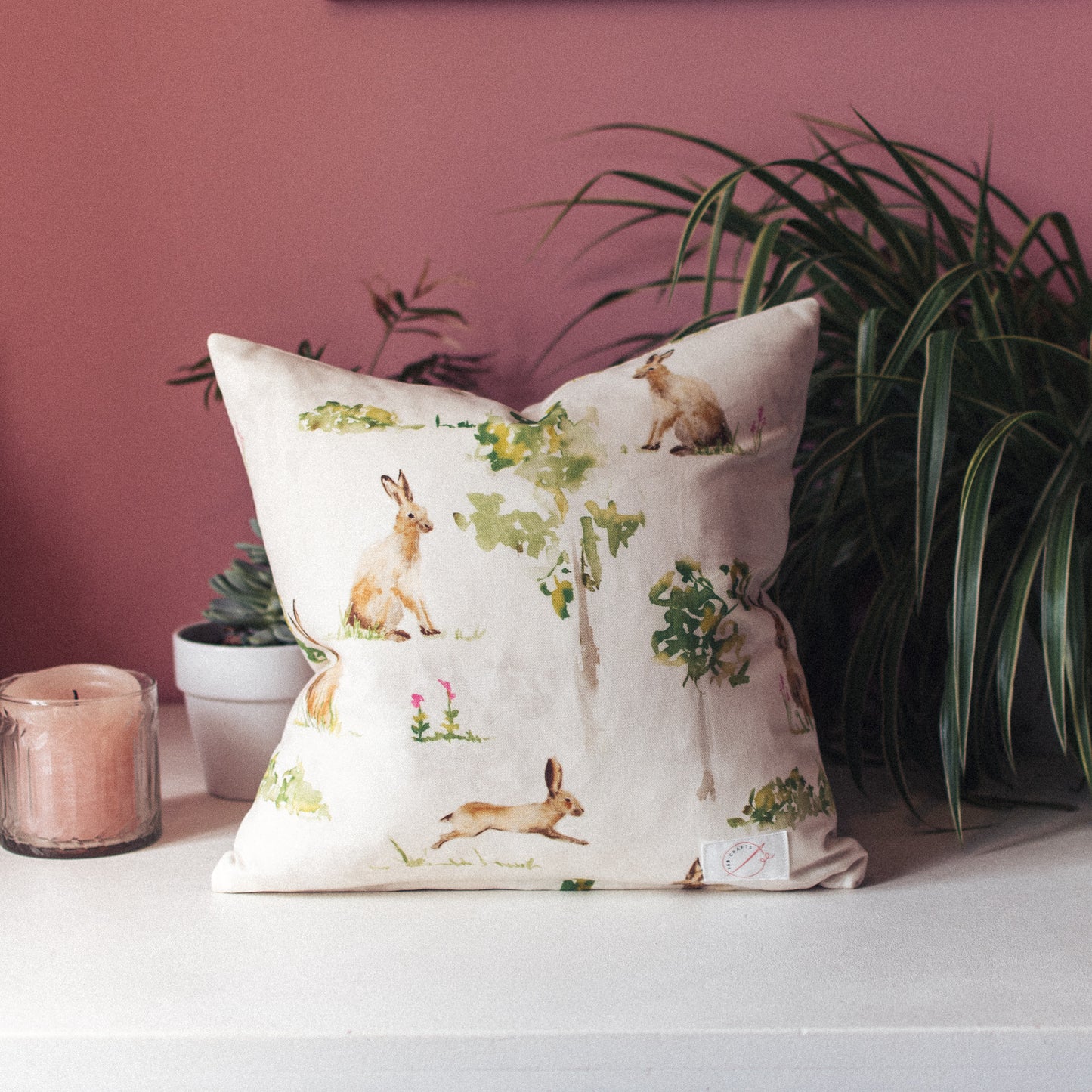 White cushion featuring water colour hares and trees by F&B Crafts