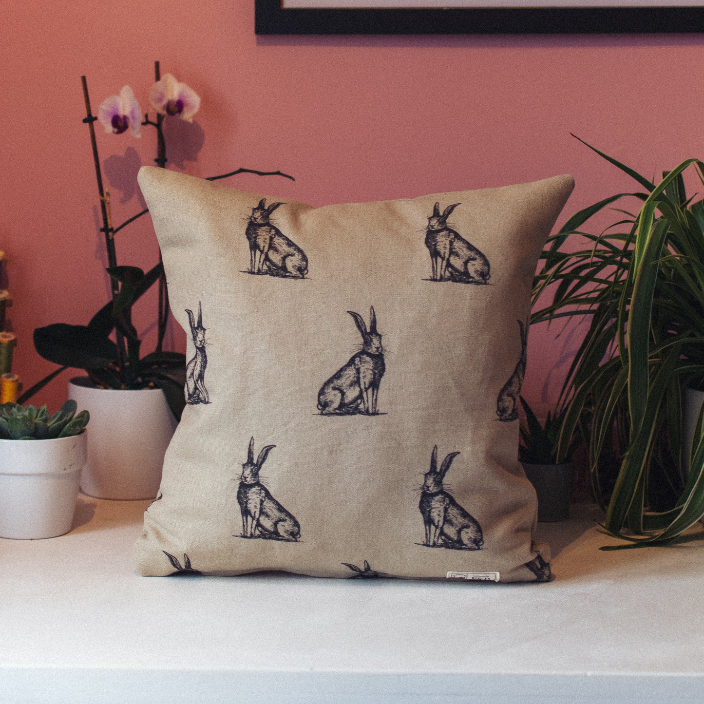 F&B Crafts - Hare Print Cushion against pink wall and green leaves